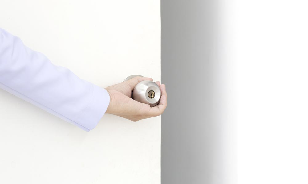 hand opening a white door with silver door knob